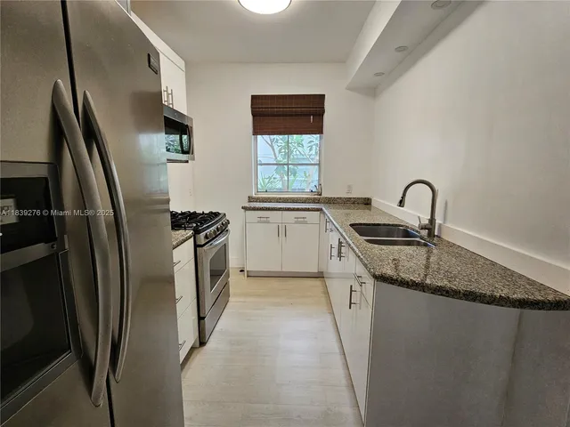 a kitchen with stainless steel appliances granite countertop a refrigerator a sink a stove and island