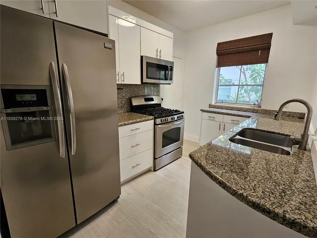 a kitchen with granite countertop a refrigerator stove and sink