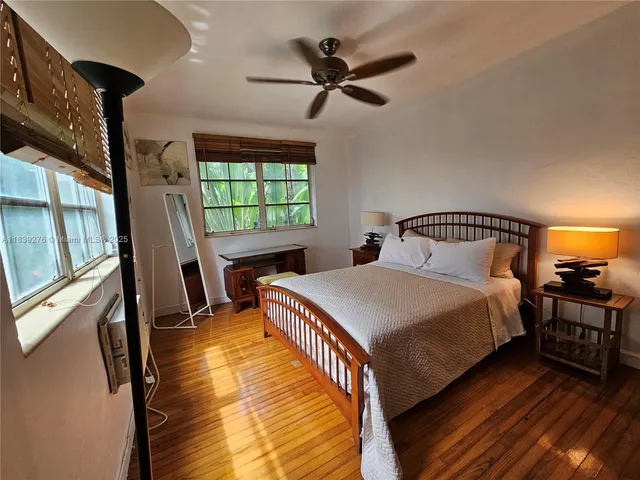 a bedroom with a bed a window and wooden floor