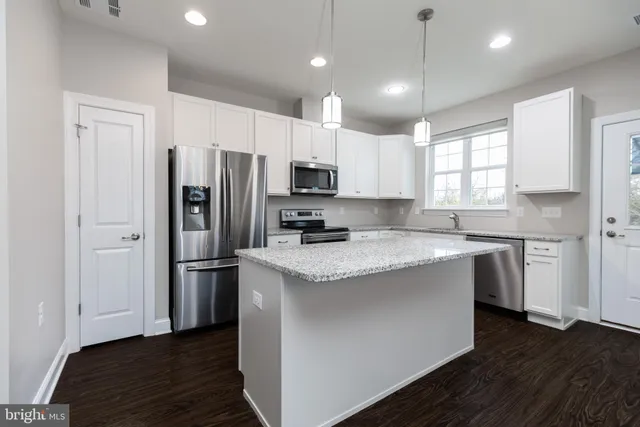 a kitchen with stainless steel appliances granite countertop a sink a stove a refrigerator a center island and cabinets