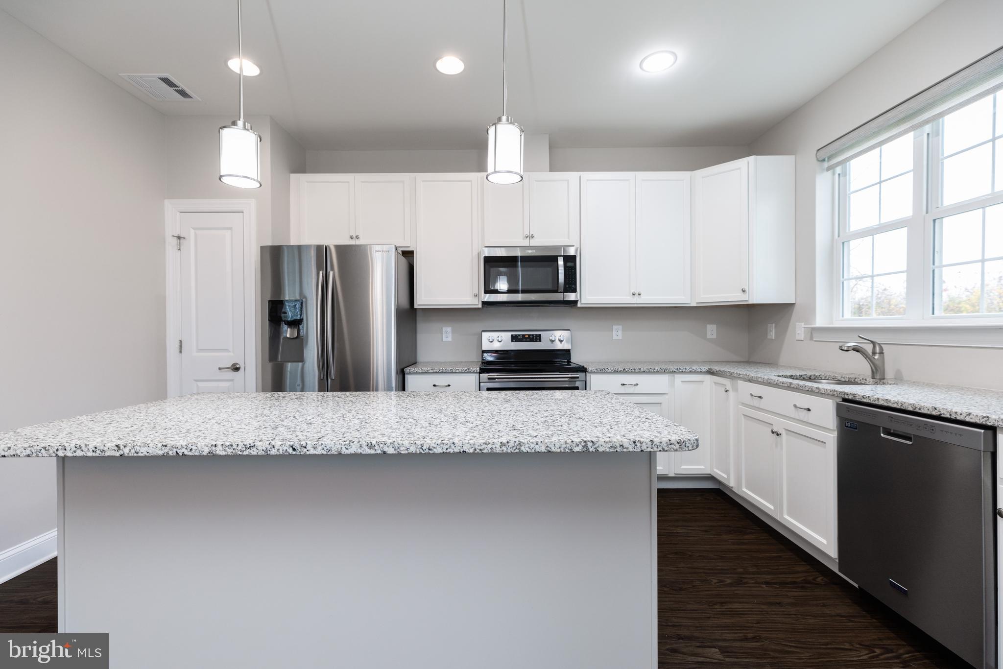 1415 Whispering Woods Road Middletown, DE 19709 - Photo 19 of 42 a kitchen with stainless steel appliances granite countertop a sink a stove a refrigerator a center island and cabinets