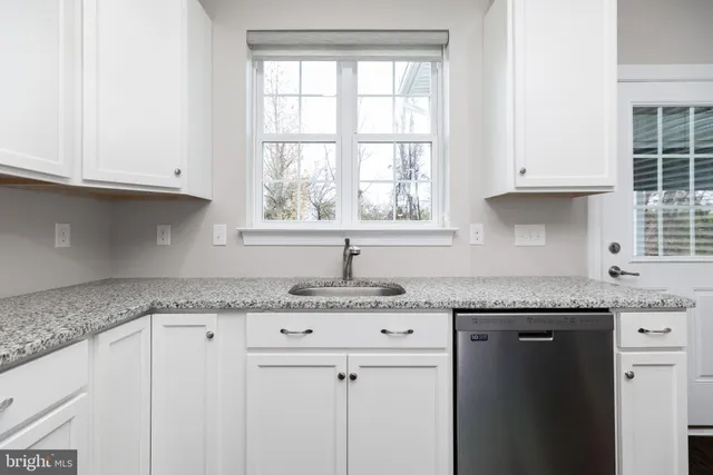 a view of kitchen with granite countertop cabinets and window