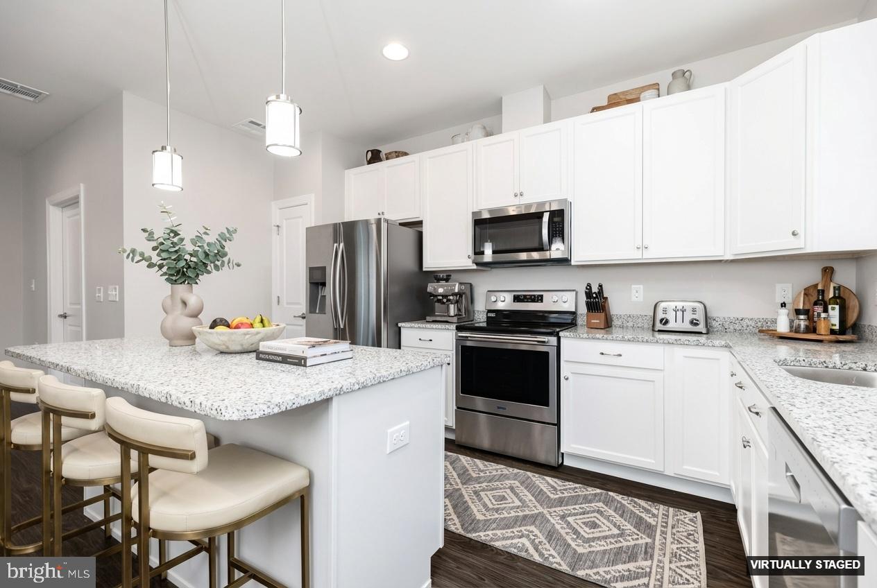 1415 Whispering Woods Road Middletown, DE 19709 - Photo 3 of 42 a kitchen with granite countertop a stove refrigerator and microwave
