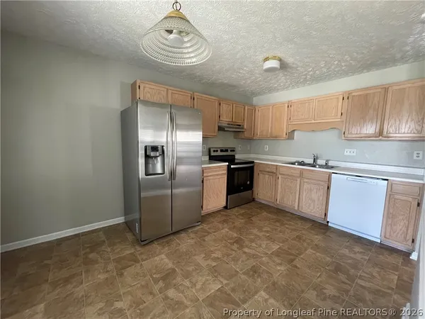 a kitchen with stainless steel appliances granite countertop a sink a stove a refrigerator cabinets and a window
