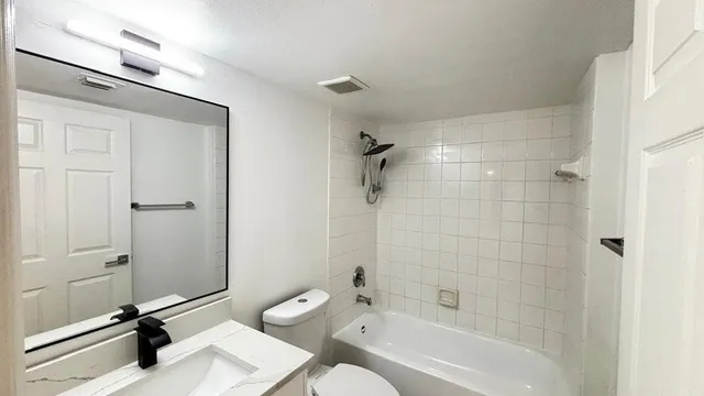 a bathroom with a bathtub shower sink vanity and a toilet
