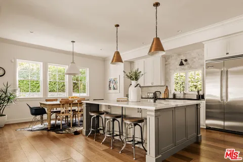 a kitchen with stainless steel appliances granite countertop a stove a refrigerator a kitchen island a dining table and chairs