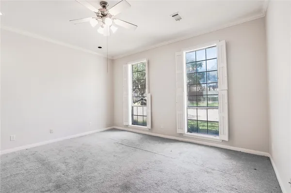 an empty room with windows and chandelier fan