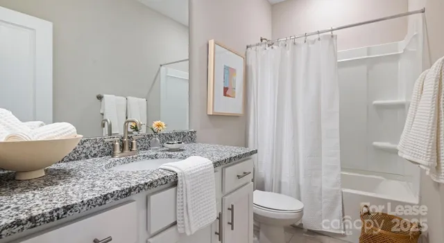 a bathroom with a granite countertop sink toilet and shower