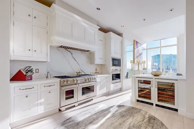a kitchen with stainless steel appliances a stove and white cabinets