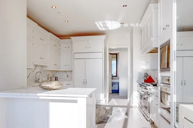 a kitchen with white cabinets and refrigerator