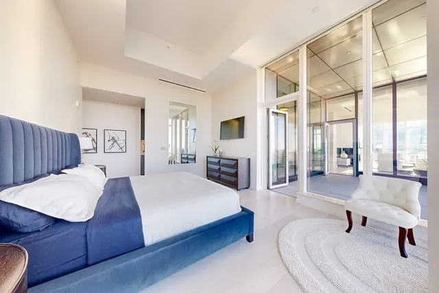 a spacious bedroom with a bed a table and large windows