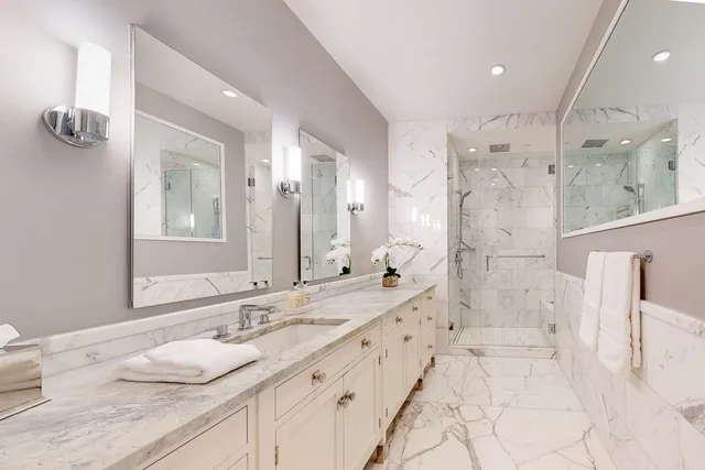 a bathroom with a granite countertop double vanity sink mirror and shower