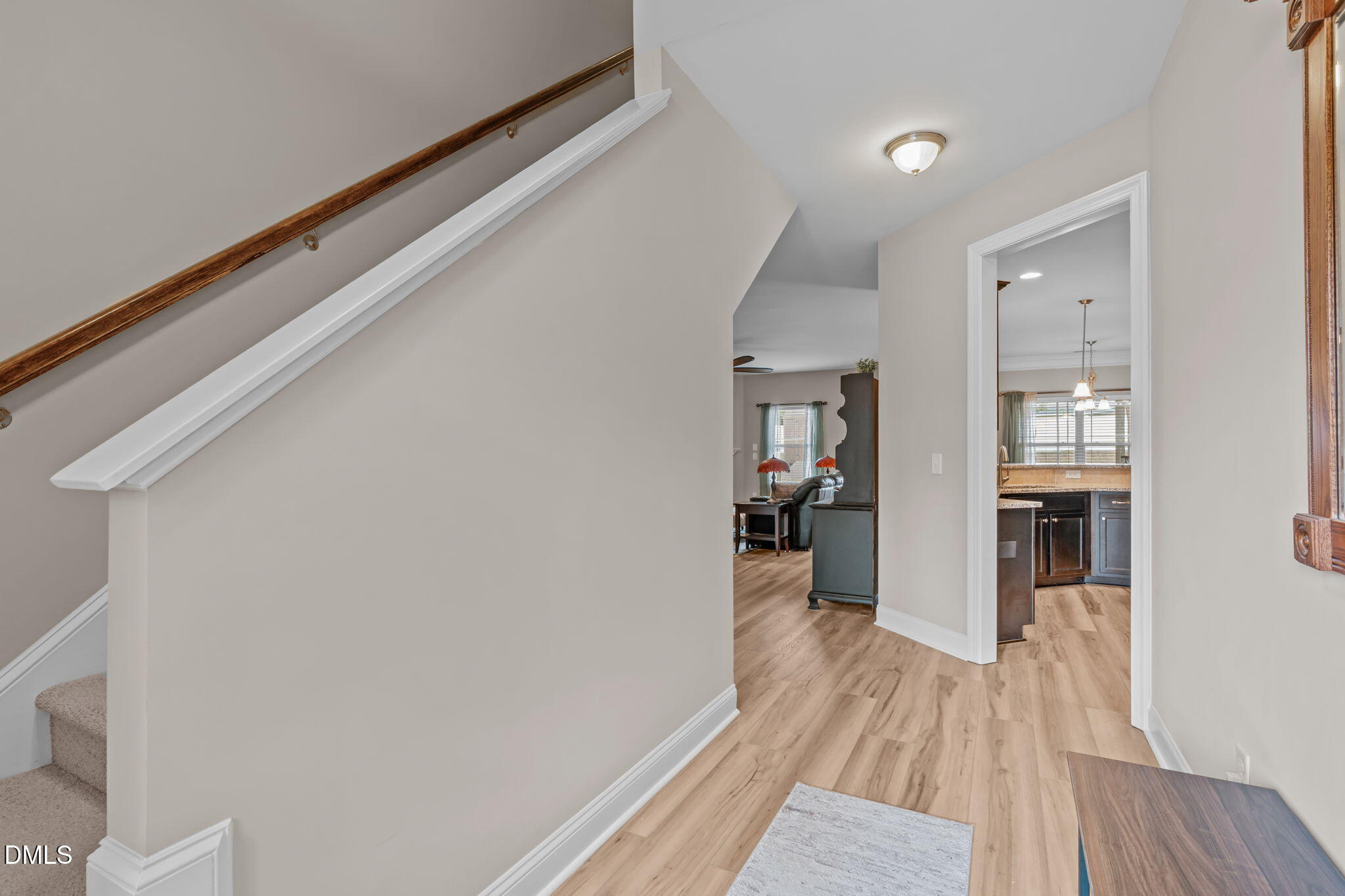 Fresh paint throughout the home, new LVP flooring downstairs, offset staircase at entry, doorways to kitchen on right and family room on left.