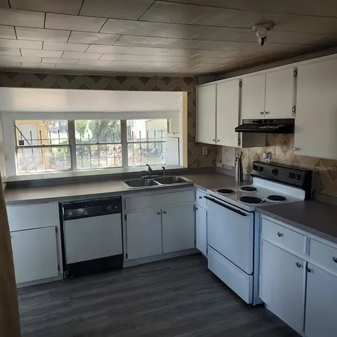 a kitchen with granite countertop white cabinets and a wooden floor