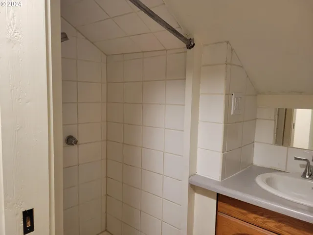 a bathroom with a sink shower and a mirror