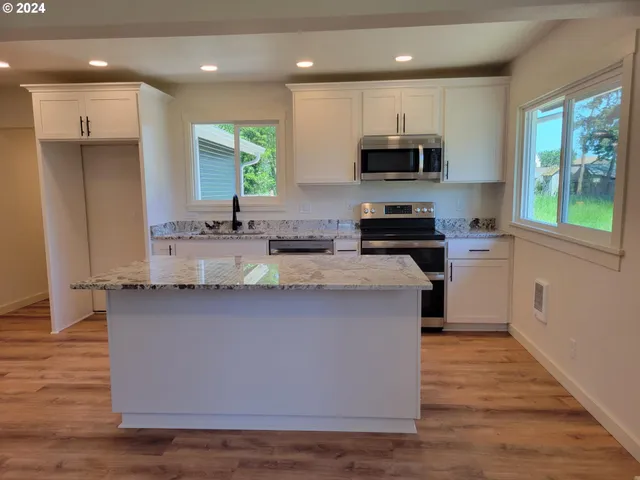 a kitchen with stainless steel appliances granite countertop a stove a sink and a microwave