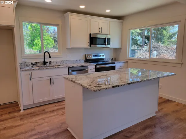 a kitchen with stainless steel appliances granite countertop a sink a stove a microwave a refrigerator and cabinets