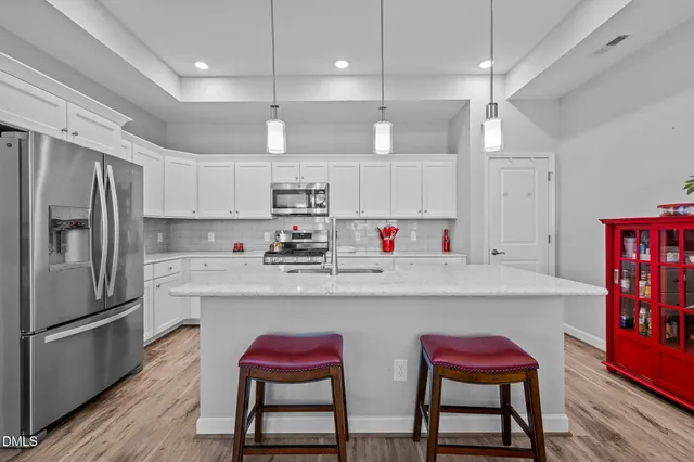 a kitchen with stainless steel appliances granite countertop a dining table chairs refrigerator and sink