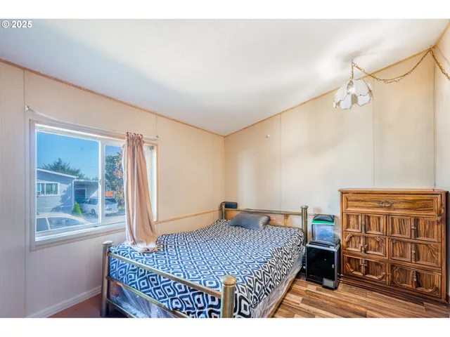 a bedroom with a bed a dresser and a window