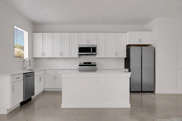a kitchen with stainless steel appliances granite countertop white cabinets a refrigerator a stove a microwave and island