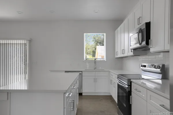 a kitchen with stainless steel appliances a sink a stove a microwave a refrigerator and cabinets