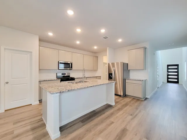 a kitchen with stainless steel appliances kitchen island a refrigerator sink and cabinets