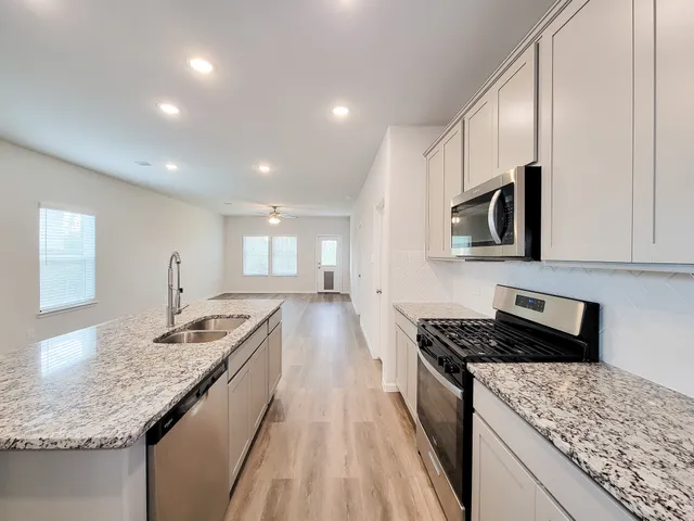 a kitchen with granite countertop kitchen island stainless steel appliances a sink stove top oven and cabinets