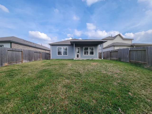 a view of a house with a yard and a large tree