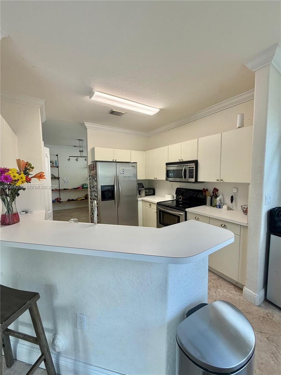15391 Southwest 17th Terrace Miami, FL 33185 - Photo 9 of 16 a kitchen with stainless steel appliances a refrigerator a sink a stove a dining table and chairs