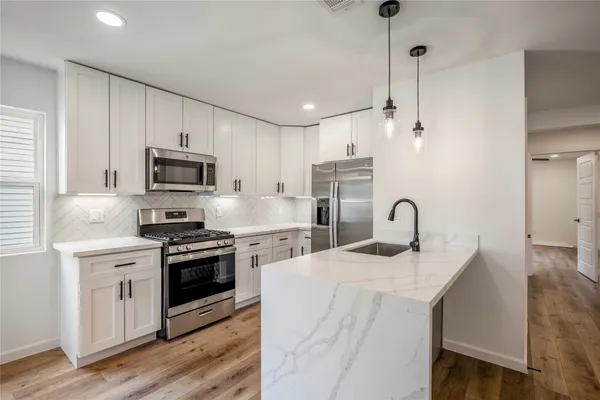 a view of a kitchen island a sink wooden floor and a large window