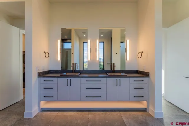 a bathroom with a granite countertop double vanity sink and a mirror