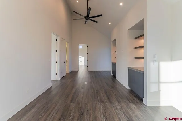 a view of a hallway with wooden floor and a refrigerator