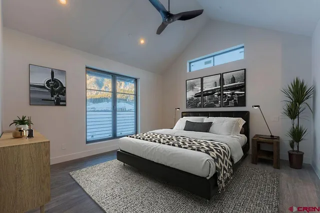 a bedroom with a large bed a potted plant and a dresser