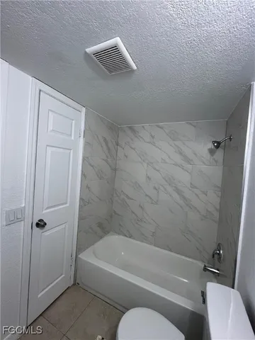 a bathroom with a toilet and white tub