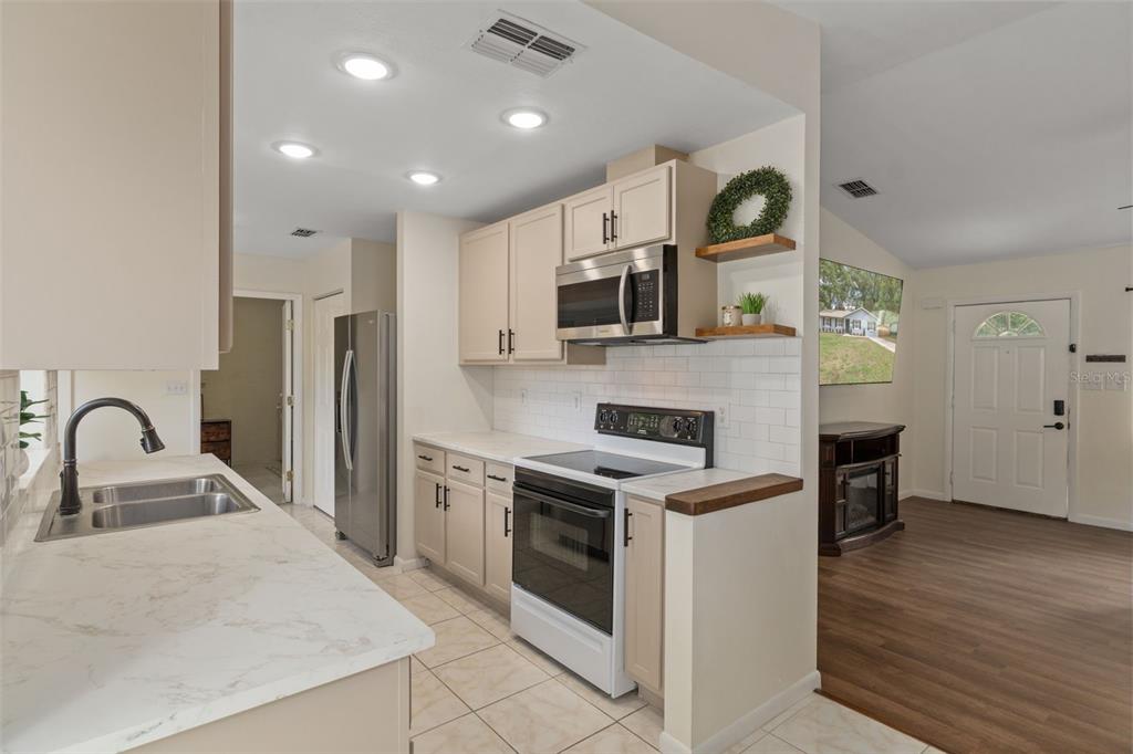 4325 South Canton Terrace Inverness, FL 34452 - Photo 5 of 35 a kitchen with stainless steel appliances granite countertop a stove top oven a sink a refrigerator and a dining table with wooden floor