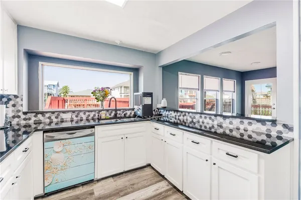 a kitchen with granite countertop a sink and white cabinets