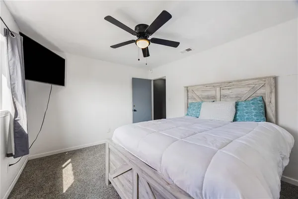 a bedroom with a bed a flat screen tv and a ceiling fan