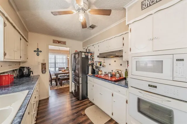 a kitchen with stainless steel appliances a stove top oven a refrigerator a dining table and chairs with wooden floor