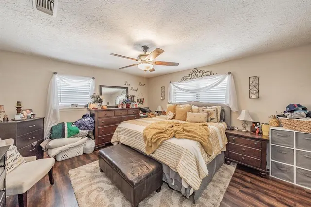 a spacious bedroom with a bed a couch and potted plant with the dresser