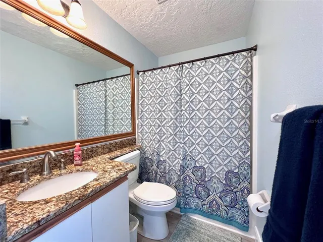 a bathroom with a granite countertop toilet and a sink