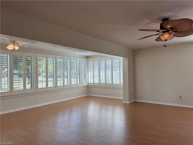 a view of an empty room with window and wooden floor