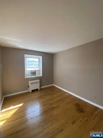 a view of a hallway with wooden floor and a bathroom