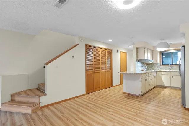 a large white kitchen with wooden floors and kitchen view