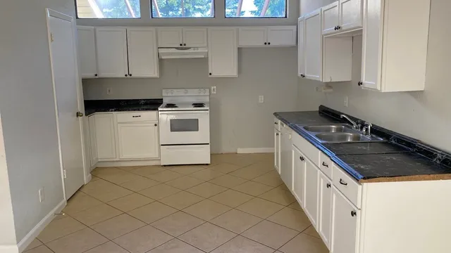 a kitchen with granite countertop white cabinets and white appliances