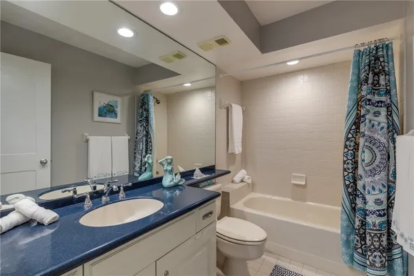 a bathroom with a granite countertop sink a toilet a tub and shower