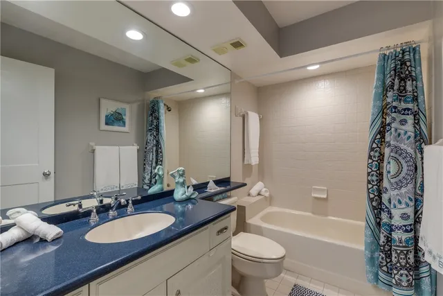 a bathroom with a granite countertop sink a toilet a tub and shower