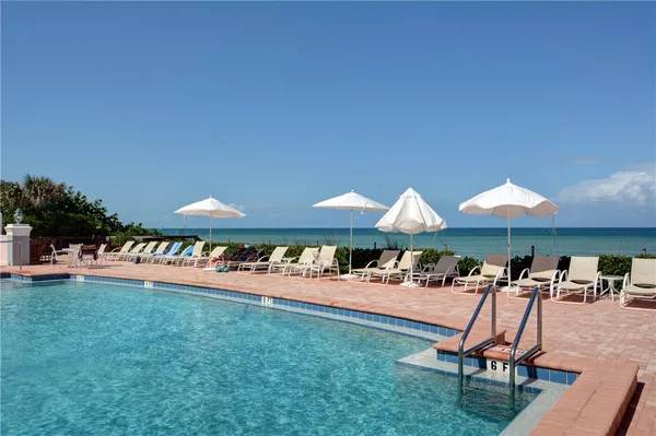 a view of a swimming pool with a table and chairs under an umbrella