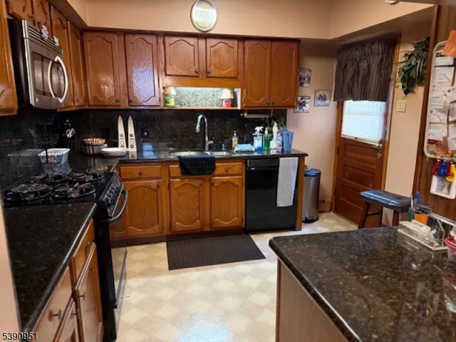 a kitchen with stainless steel appliances granite countertop a stove a sink dishwasher and cabinets with wooden floor