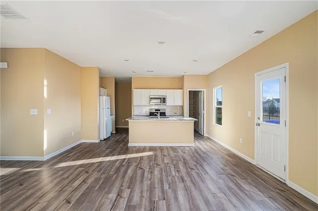 a view of a kitchen with kitchen island wooden floor stainless steel appliances and cabinets