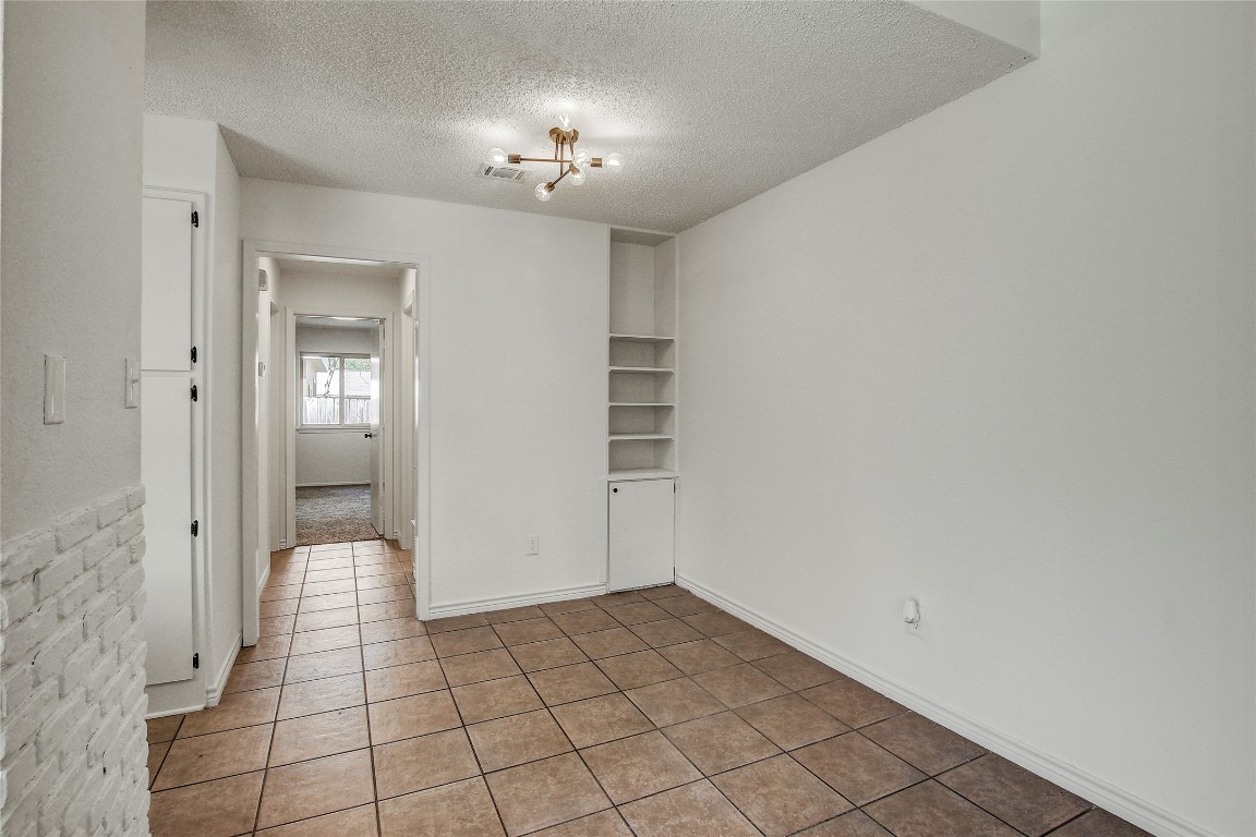 902 King Albert Street, Unit A Austin, TX 78745 - Photo 11 of 19 Tiled spare room featuring a textured ceiling and a chandelier